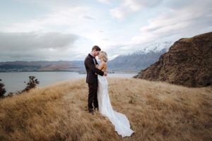 bride and groom cuddle on mountain top Bayonet Peaks Queenstown New Zealand