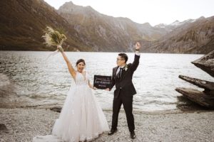 Bride and groom hold a just married sign and celebrate after elopement at Lochnagar in Queenstown, New Zealand