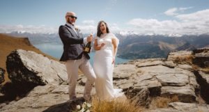Bride and groom pop champagne to celebrant eloping on top of a mountain in Queenstown New Zealand
