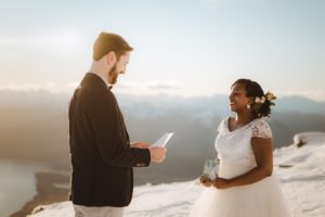Bride and groom read their vows at winter wedding in snow on top of Queenstown mountain