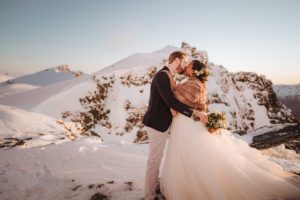 Bride and groom kissing in the snow on top of a mountain in Queenstown New Zealand
