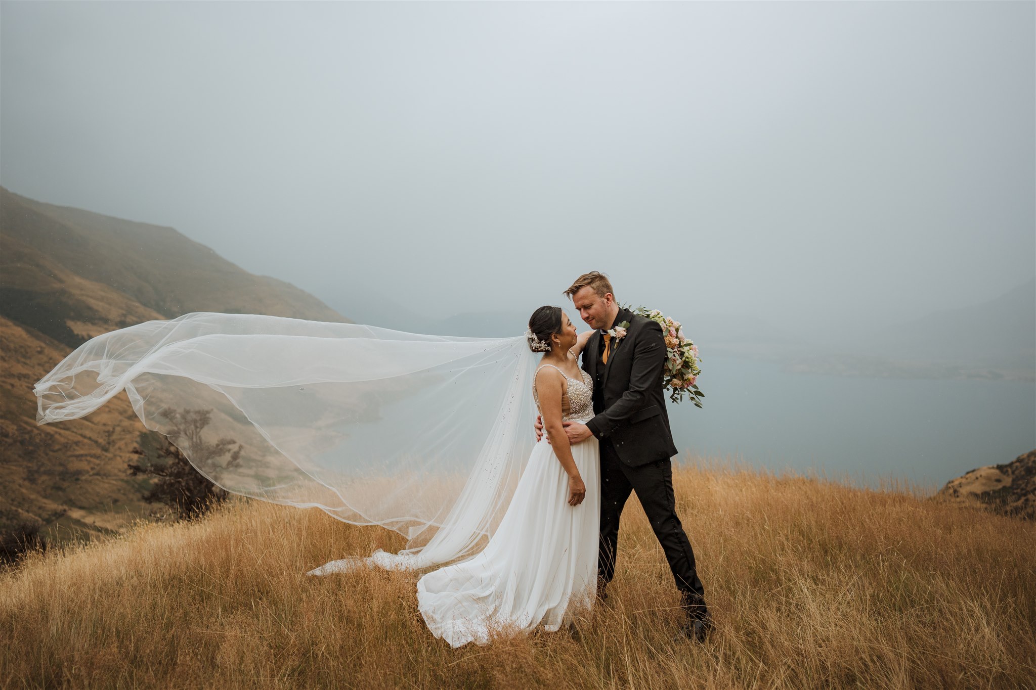 bride and groom on mountain in Queenstown in the rain