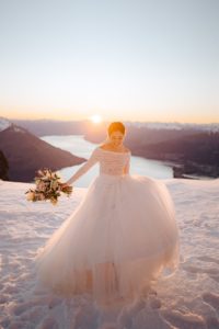 bride plays with her wedding dress in the snow at sunset at The Remarkables in Queenstown New Zealand