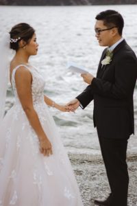 close up photo of groom reading wedding vows to bride beside alpine lake in Queenstown New Zealand