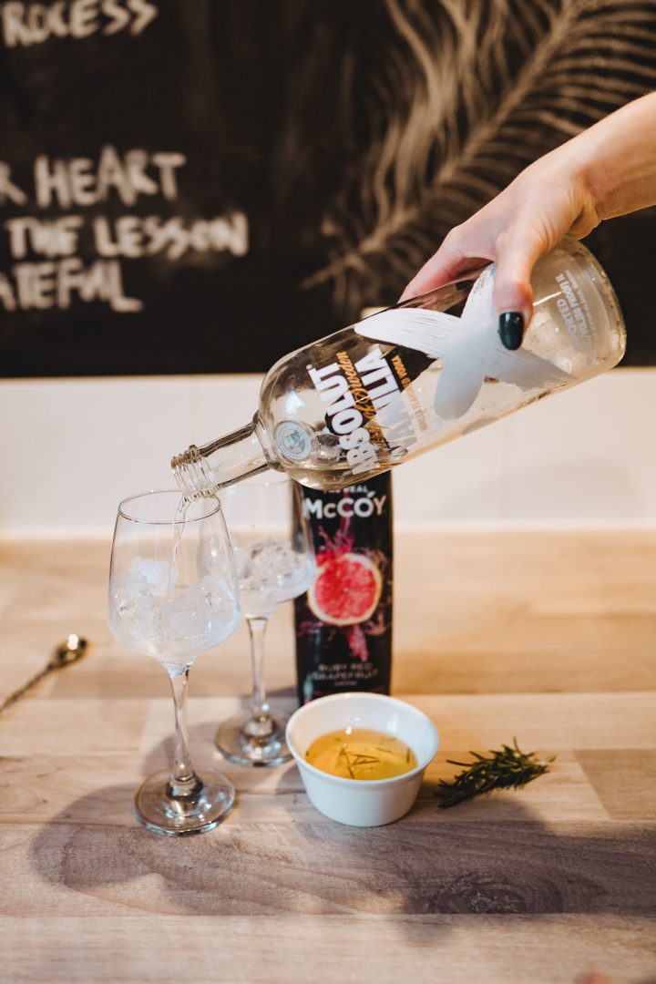 adding vodka to vodka grapefruit and rosemary cocktail