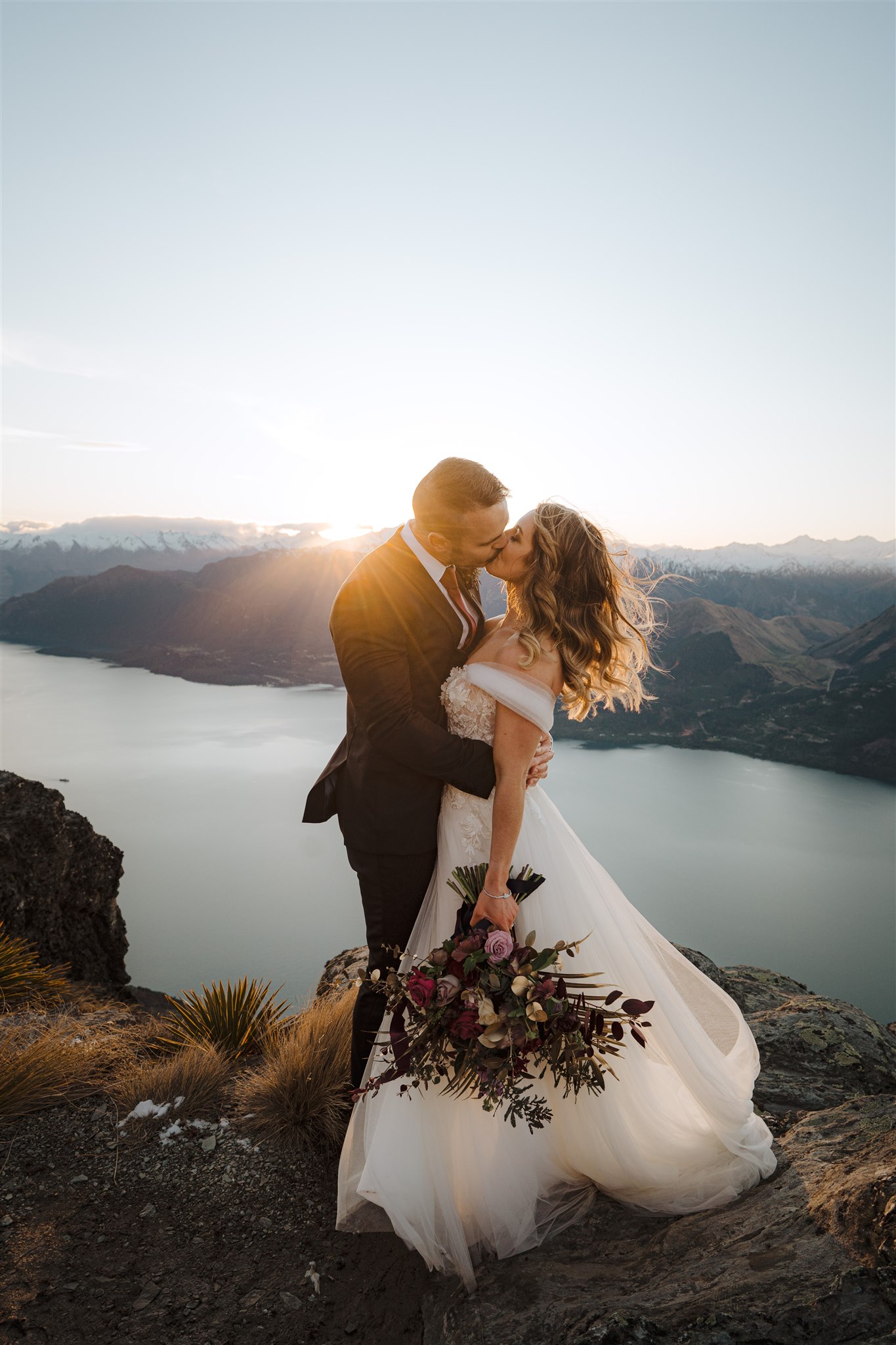 bride and groom kiss at sunset after wedding ceremony at Cecil Peak in Queenstown, nNew Zealand