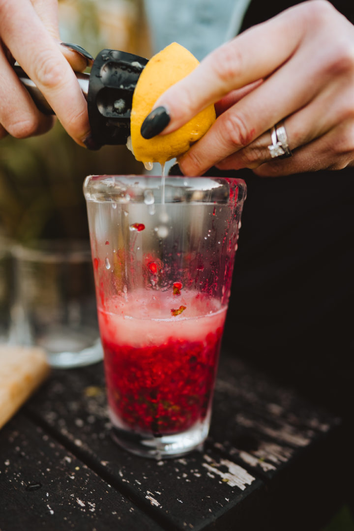 adding lemon juice to a raspberry mojito cocktail