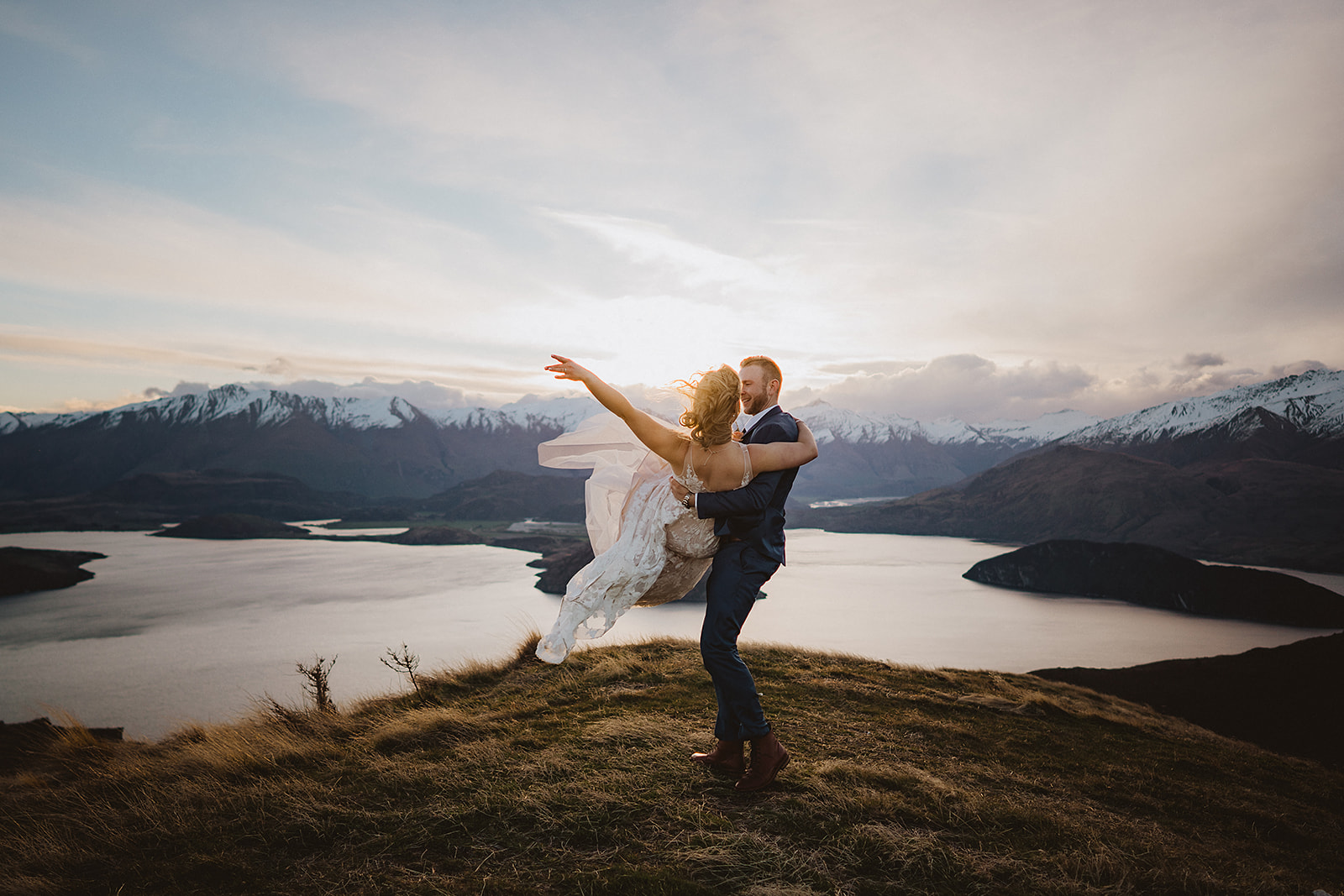 groom picking up bride at sunset at the peninsula in Wanaka New Zealand