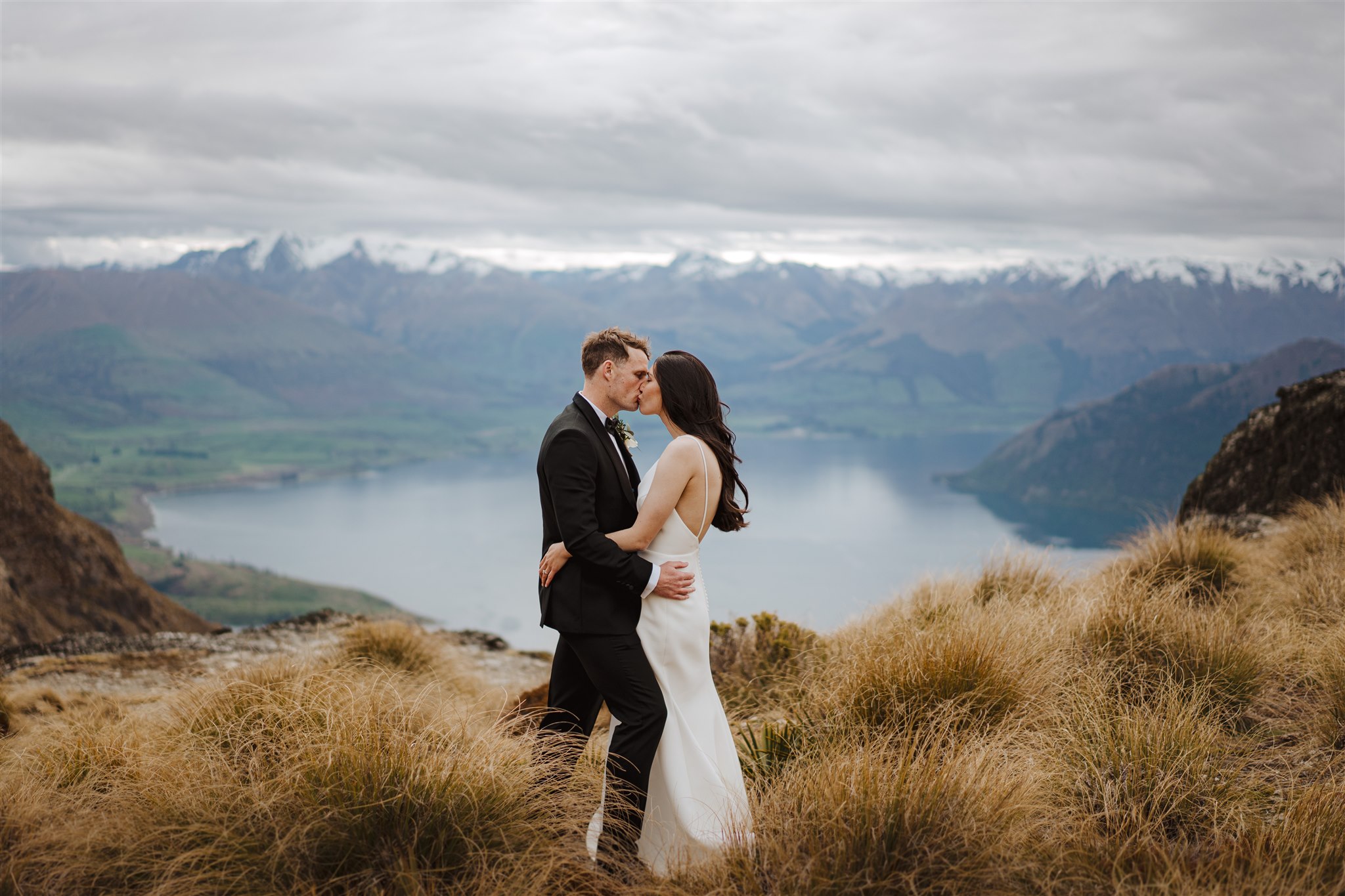 Bride and groom cuddle on a mountain top in Queenstown New Zeland