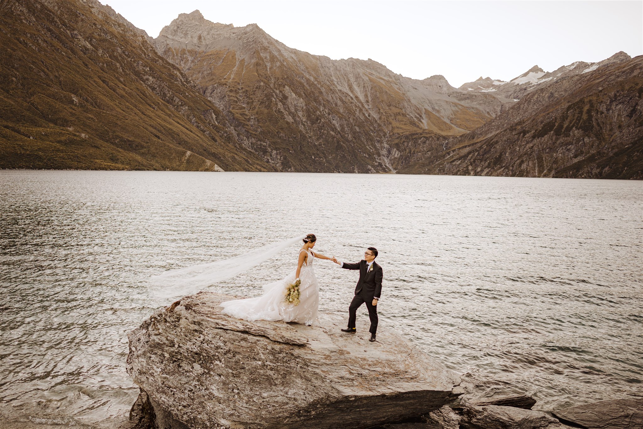 Bride and groom explore alpine lake Lochnagar in Queenstown New Zealand