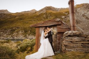 bride and groom pose for photos at hunting hut at Lochnagar Queenstown