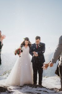 newlywed couple walk through snow confetti at winter wedding in queenstown new zealand
