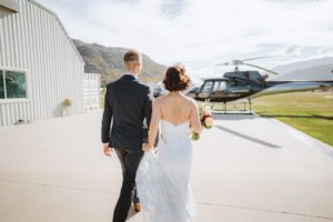 bride and groom walking towards helicopter read for mountain top wedding