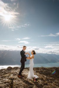 bride and groom cheers with champagne after mountain top wedding ceremony on Mount Crichton in Queenstown New Zealand
