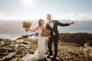 bride and groom dance with elopement announcement sign after wedding ceremony on Mount Crichton in Queenstown New Zealand