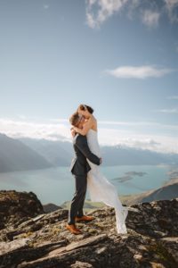 groom lifting bride up for a kiss at Mount Crichton, Queenstown, New Zealand