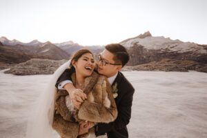 bride and groom cuddle and laugh at glacier wedding in Queenstown, New Zealand