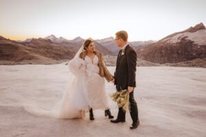 bride and groom hold hands at Tyndall Glacier at suset in Queenstown New Zealand