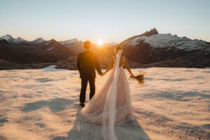 bride and groom hold hands at sunset on Tyndall Glacier in Queenstown, New Zealand