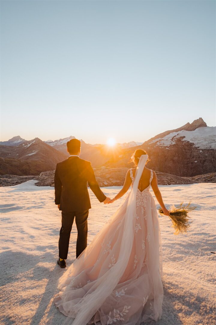 bride and groom hold hands at sunset on Tyndall Glacier in Queenstown, New Zealand